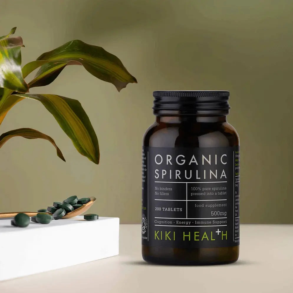 Spirulina Tablets, Organic - Kiki Health in a dark bottle with green leaves in the background, 200 tablets, 500mg.